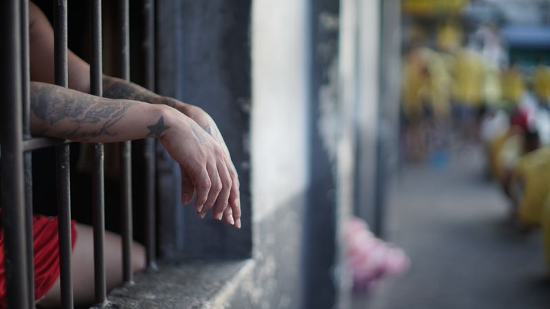 Tattooed arm reaching through prison bars
