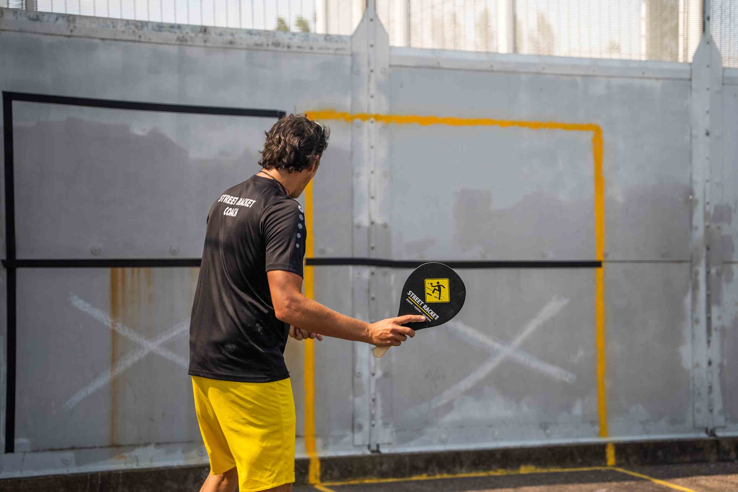 Street Racket coach playing against a wall with marked playing area