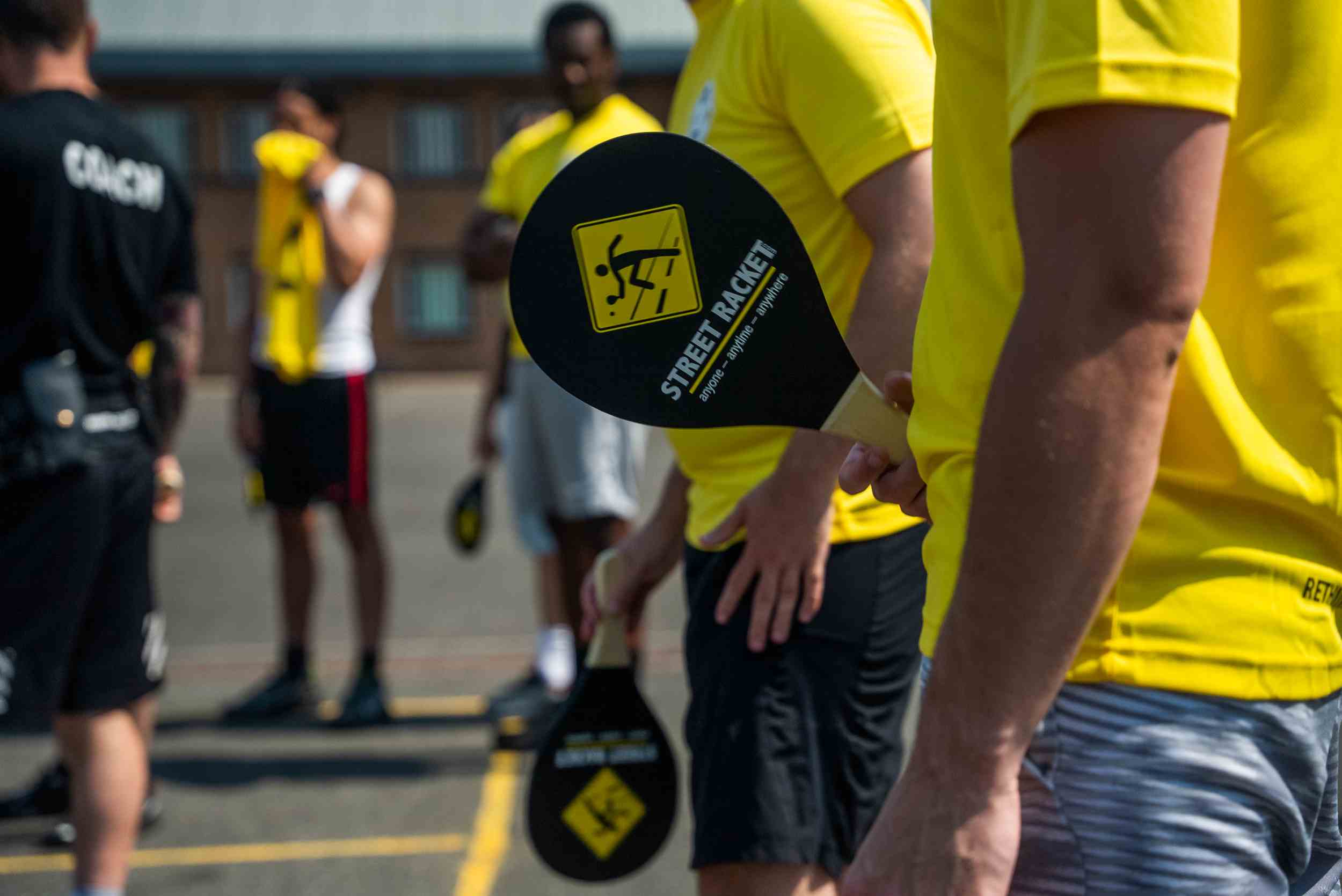 Street Racket paddle being held by a player in a yellow shirt